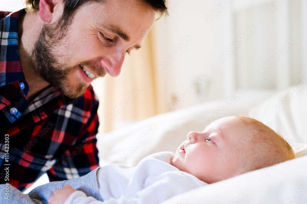 Baby boy lying on bed, with his father Baby boy lying on bed, with his father