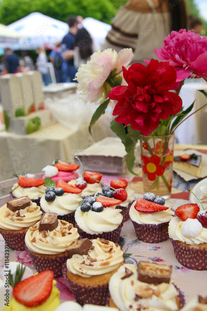 Delicious vanilla cupcake with strawberry frosting and fresh strawberries and blueberries with peonies