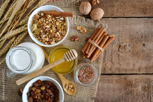 Walnuts, granola, milk and honey on wooden background