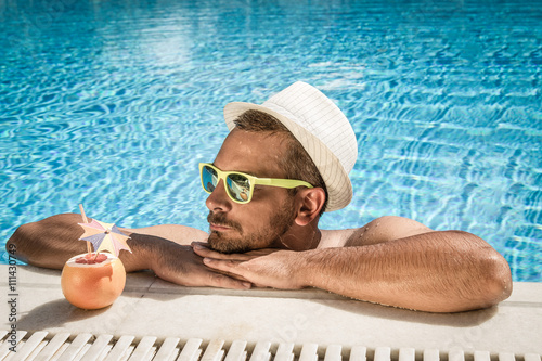 Photography Portrait of a handsome man resting at the edge of a swimming pool