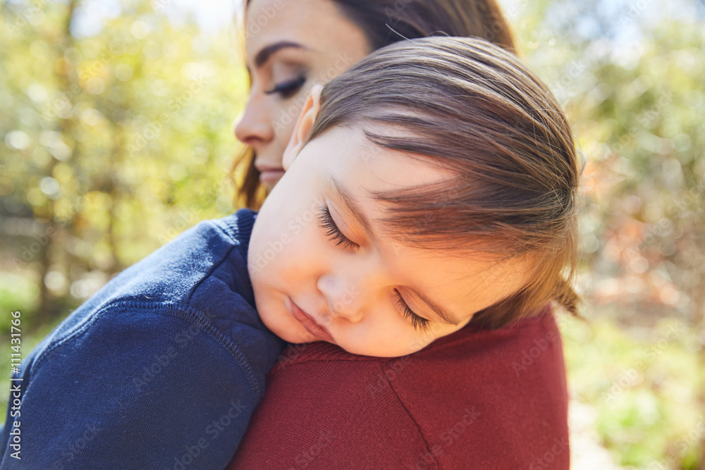 Mother holding kid boy sleeping in her shoulder Mother holding kid boy sleeping in her shoulder