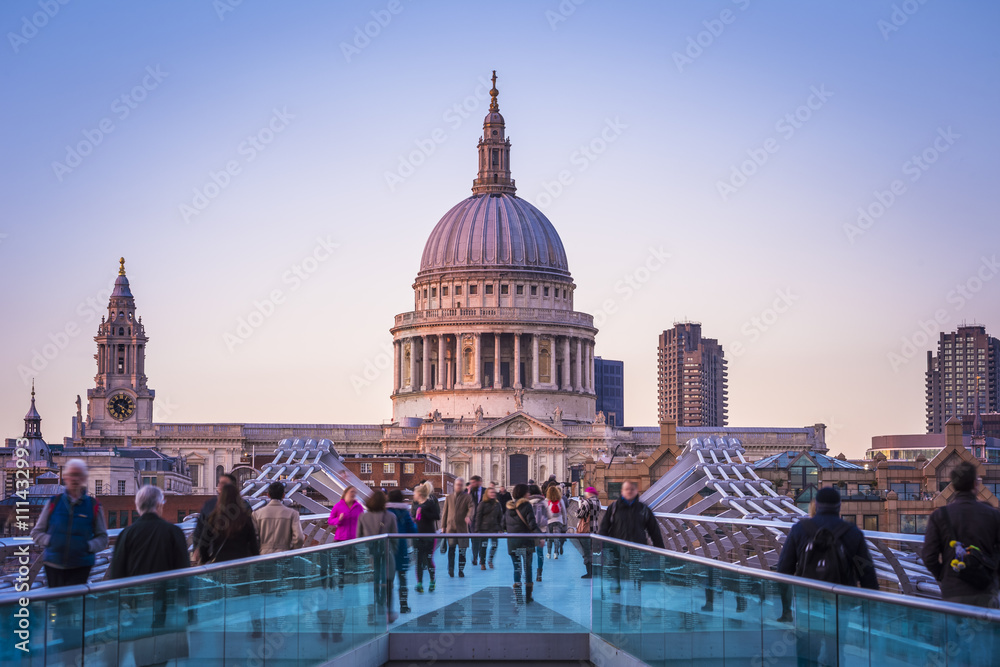 Londoners walking through Millennium Bridge after sunset - London, UK