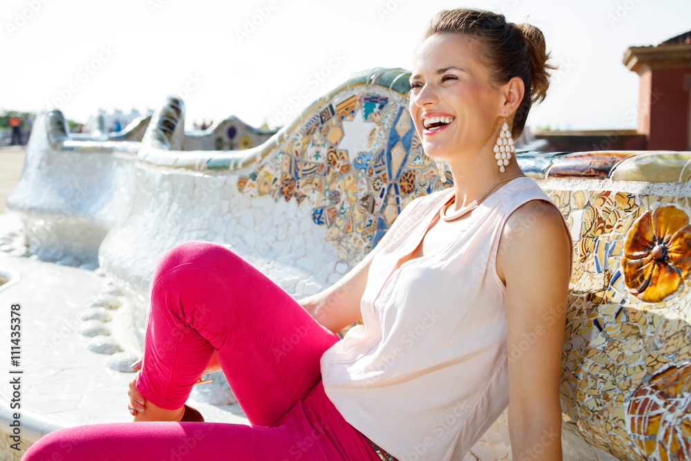 Happy young woman relaxing on the famous trencadis style bench