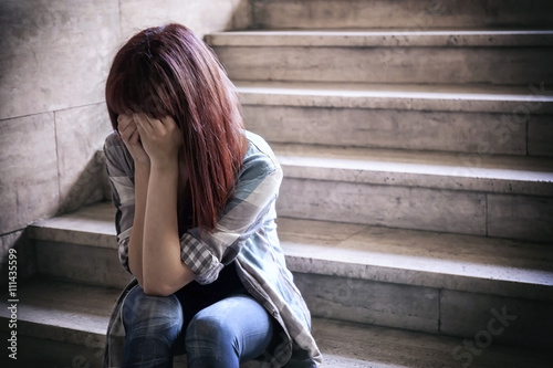 Depressed girl. Adolescent crisis sitting on the steps of a basement, covers her face with her hands. © Gennaro Leonardi