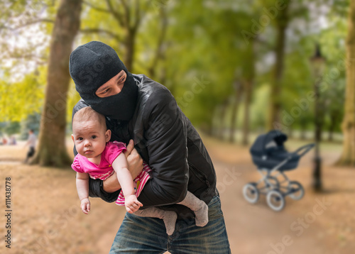 Thief is stealing kidnapped baby from stroller in park. Children kidnapping concept. photo