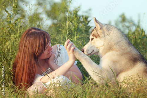 Young beautiful girl playing with a dog. Playing with the dog on the field. Close-up portrait. Siberian husky.