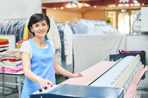 Woman Laundry worker pats the linen on the automatic machine at the dry cleaners