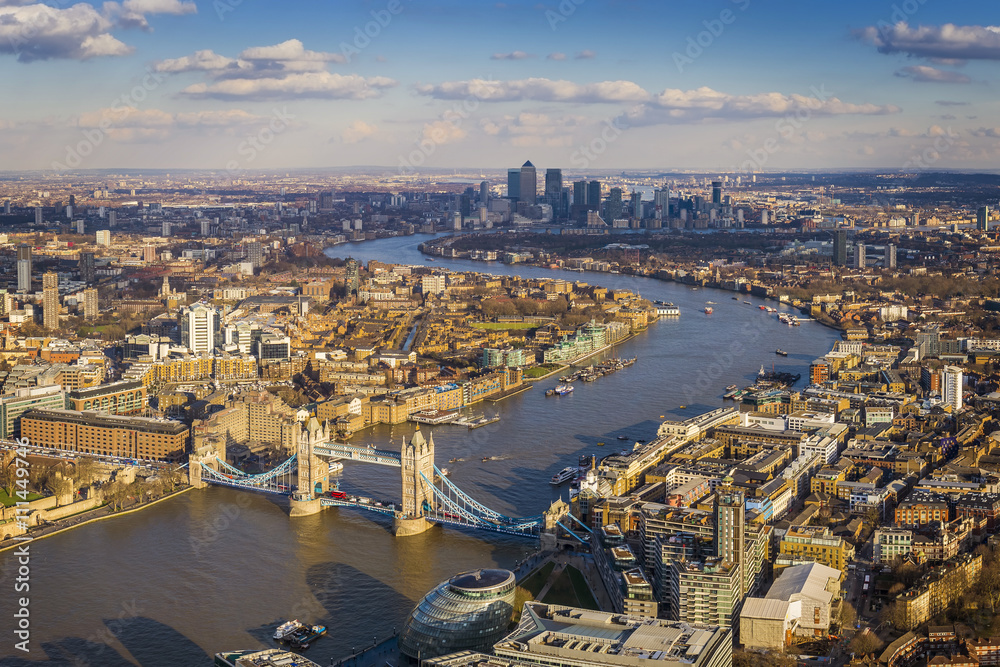 London aerial skyline view including Tower Bridge with red Double Decker Bus, skyscrapers of Canary Wharf and River Thames