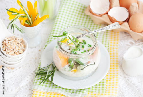 Breakfast: coddled eggs with green beans, yellow pepper, chives and rosemary in a glass jar. Selective focus. photo