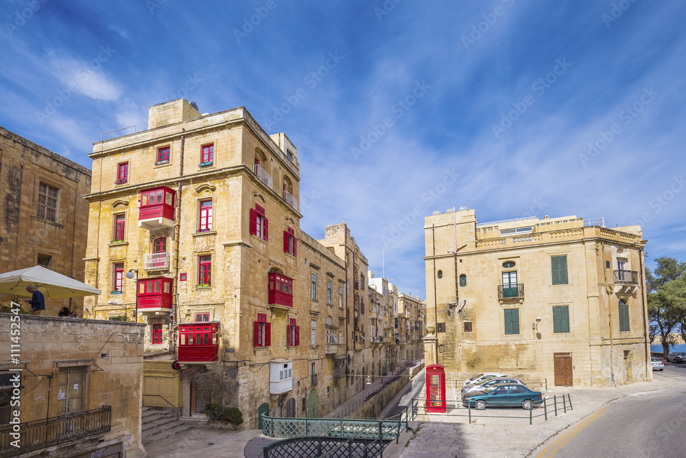 Malta, Valletta - Ancient maltese buildings with red telephone box and traditional red balconies, windows