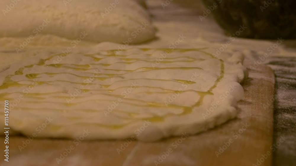 Baker pours olive oil on dough pizza. Baker pours olive oil on dough pizza.