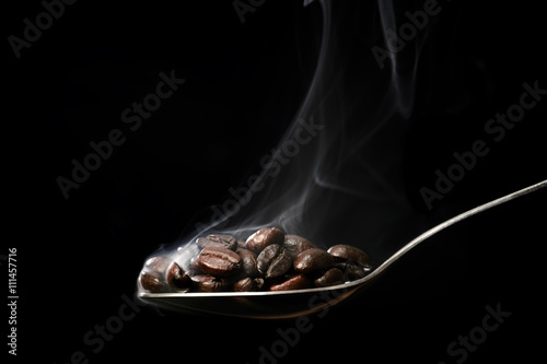 Scooping hot coffee beans with spoon.