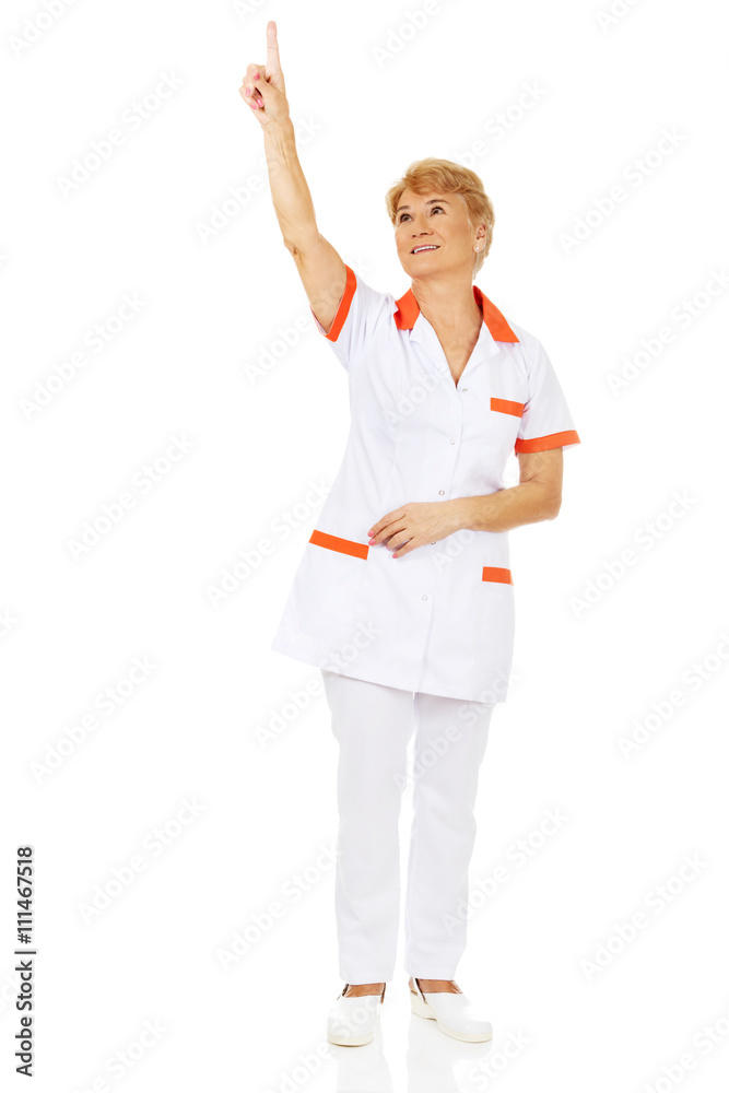 Smile elderly female doctor or nurse pointing up Smile elderly female doctor or nurse pointing up