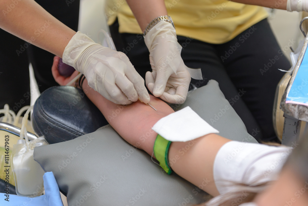 Nurse giving an intravenous injection to blood donor at blood donation