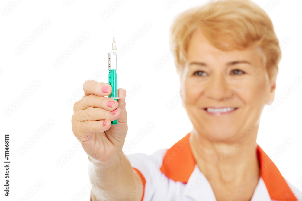 Smile elderly female doctor or nurse holds syringe Smile elderly female doctor or nurse holds syringe