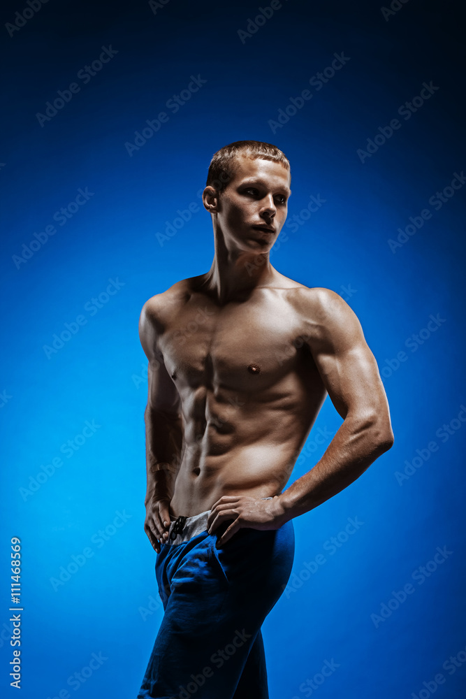Fototapeta premium Fit young man with beautiful torso on blue background