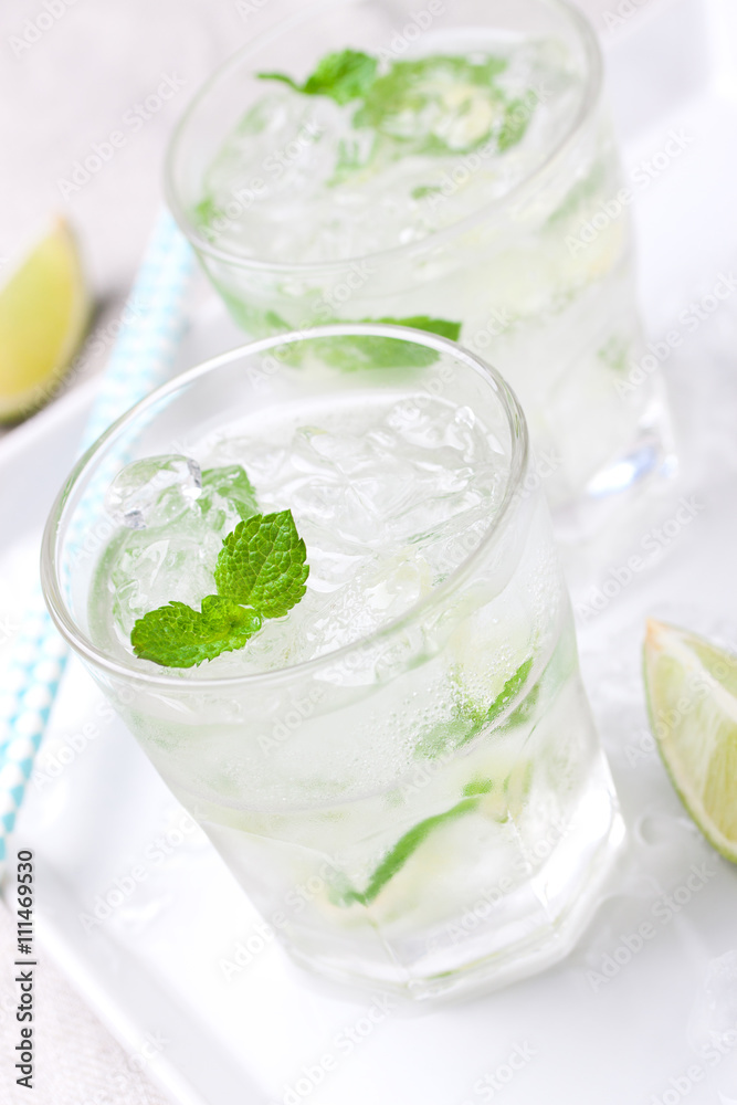 Non alcohol cold mojito cocktail with fresh lime, mint and crushed ice on a kitchen background, closeup Non alcohol cold mojito cocktail with fresh lime, mint and crushed ice on a kitchen background, closeup