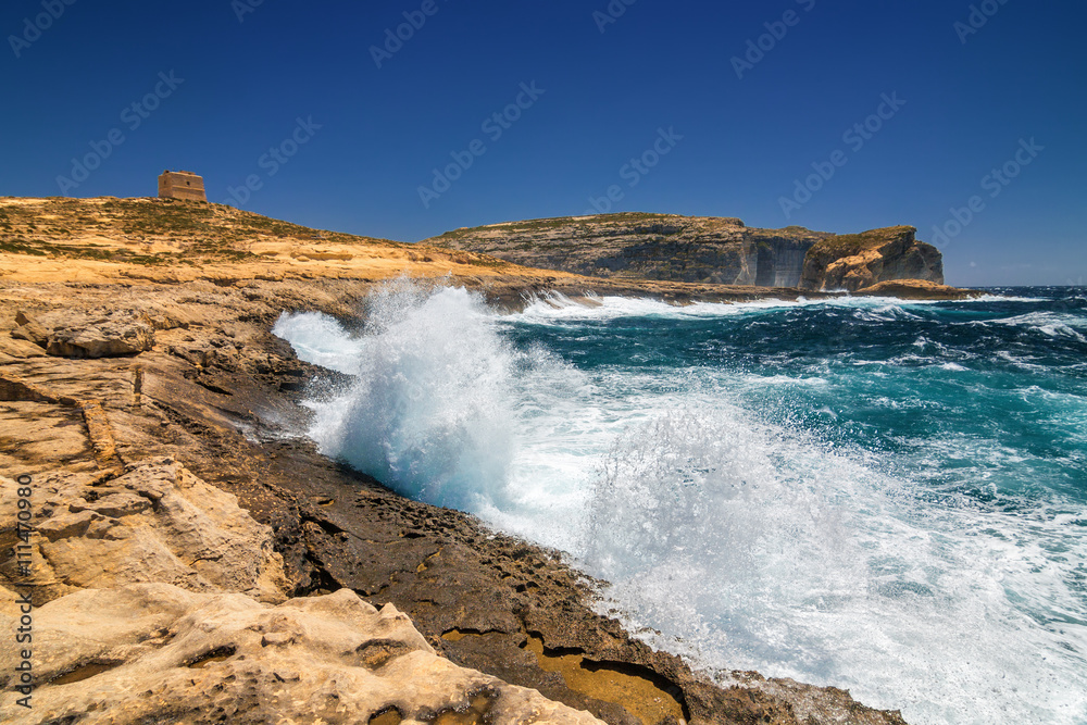 Surging waves break on the rocky shore of Dwejra bay in Gozo, Malta.