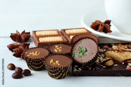 candies and chocolates with cinnamon and anise with coffee beans on white wooden background with Cup of strong coffee