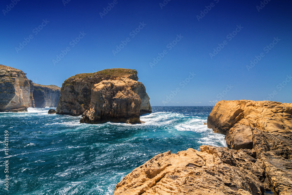 Surging waves break on the rocky shore of Dwejra bay in Gozo, Malta.