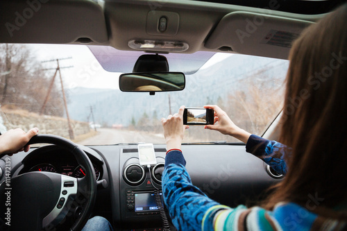 Couple driving in car and taking photos with smartphone
