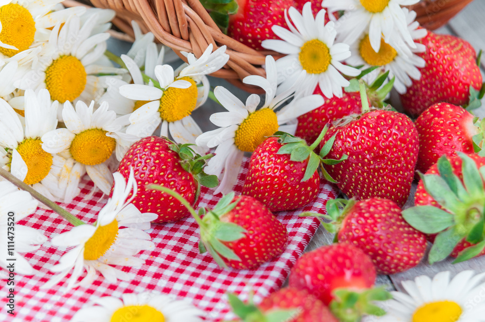 Basket of fresh ripe sweet strawberries with daisies