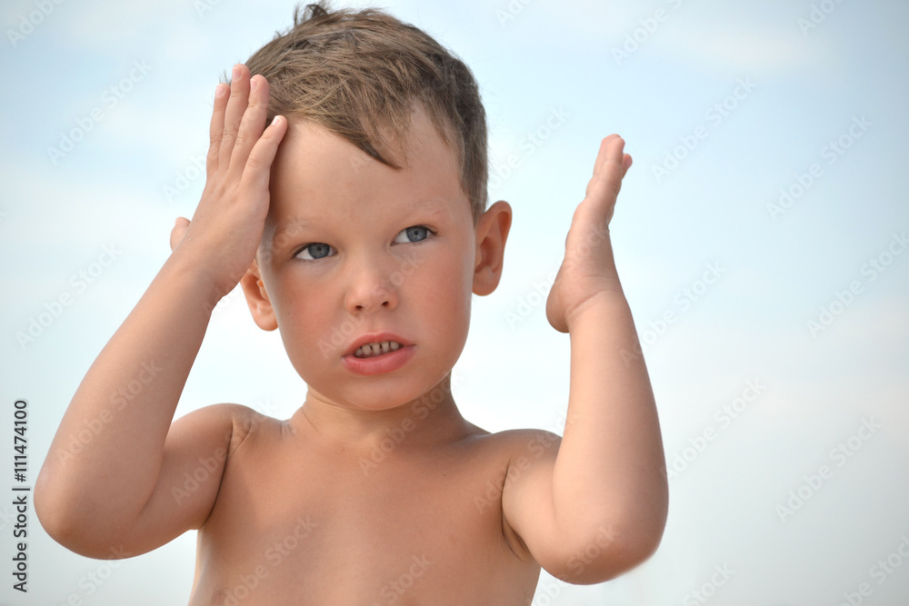 The little boy is too hot in the sun without a hat. The child has a headache. The child holds