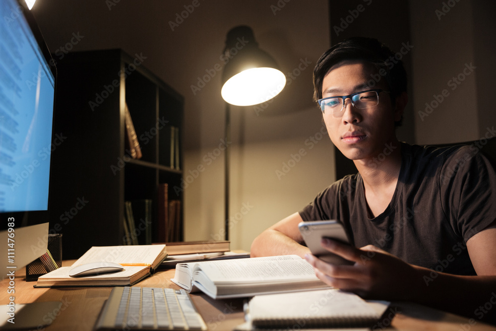 Handsome man studying and using smartphone in the evening
