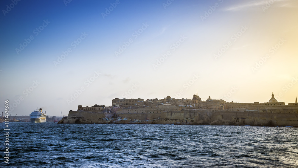 Valletta, Malta - Cruise ship leaving the Grand Harbour of Valletta at sunset