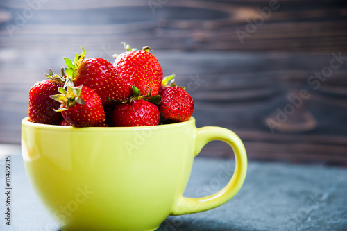 strawberry fruit in yellow cup on wooden background