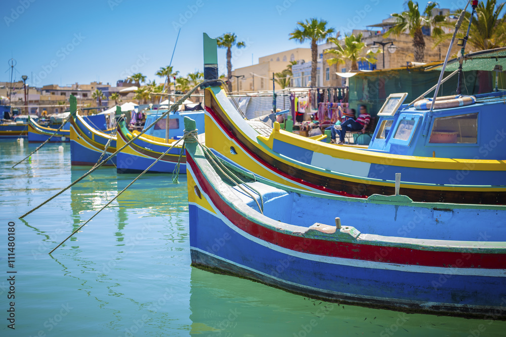 Malta - Colorful Mediterranean traditional Luzzu fishing boat at Marsaxlokk on a sunny summer day with green sea