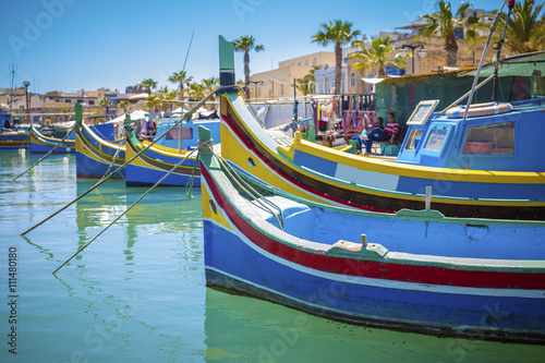 Malta - Colorful Mediterranean traditional Luzzu fishing boat at Marsaxlokk on a sunny summer day with green sea