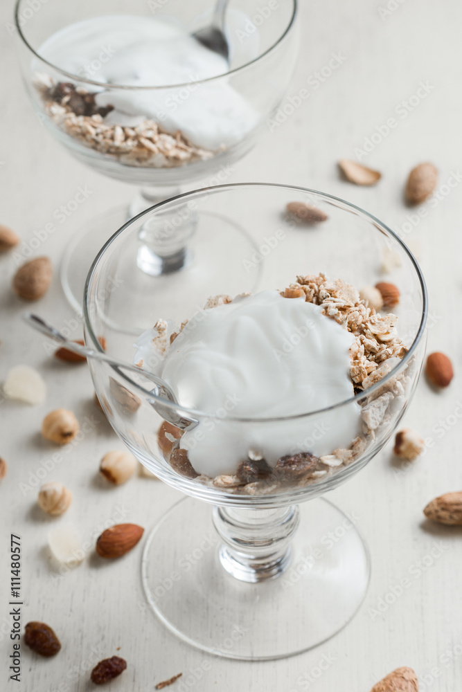 Granola with yoghurt, nuts and fruits in glass bowl on light background. Delicious, healthy sweet dessert for breakfast. Cereal, muesli. Copy space, closeup. Granola with yoghurt, nuts and fruits in glass bowl on light background. Delicious, healthy sweet dessert for breakfast. Cereal, muesli. Copy space, closeup.