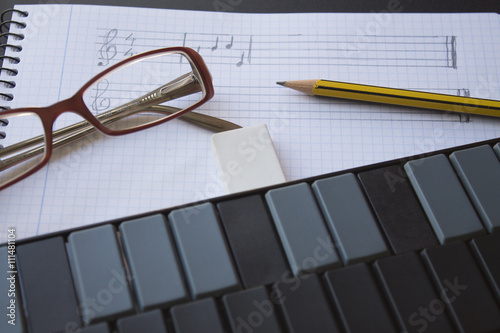 gafas, lápiz y teclado musical sobre cuaderno