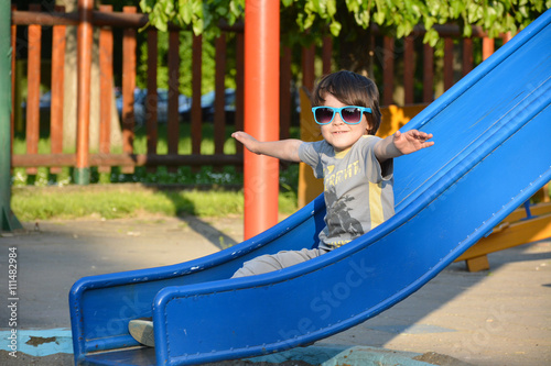 Fototapeta Naklejka Na Ścianę i Meble -  enjoy life, smiling boy with sunglasses enjoys sliding down a toboggan 