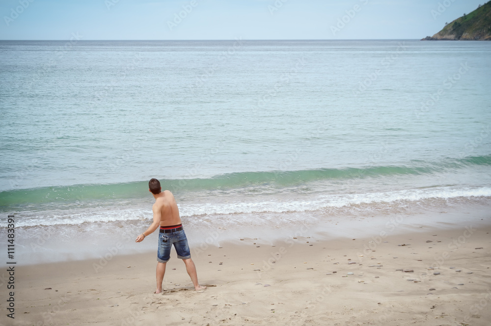 Man plays throwing rocks at the beach on vacation