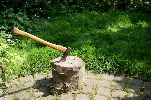 Chopping block with woodcleaver axe in a garden.