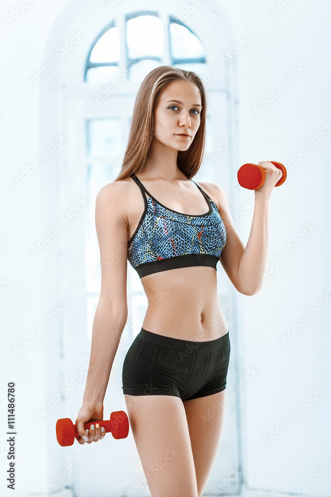 Sporty woman doing aerobic exercise with red dumbbells Sporty woman doing aerobic exercise with red dumbbells