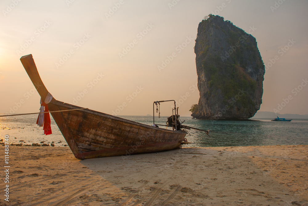 Naklejka premium Long tail boat on tropical beach with limestone rock. Sunset, island Taming. Krabi, Thailand.