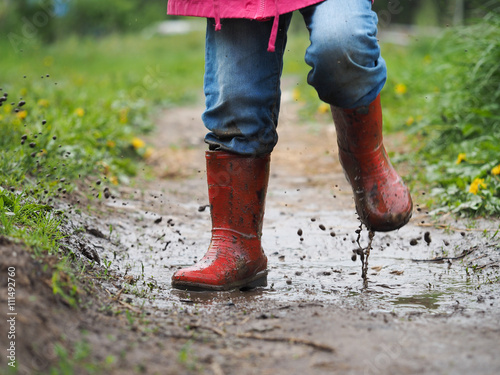 child's feet in the muddy, wet jeans and rubber boots. The child jumps in a  puddle Stock-Foto | Adobe Stock