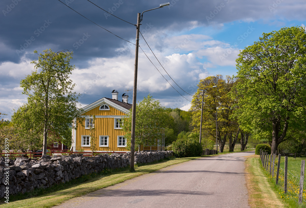 Ländliche Bebauung in Schweden mit alten , gelb gestrichenen Bauernhaus unter dramatischem Himmel. Småland, Kronobergs Län