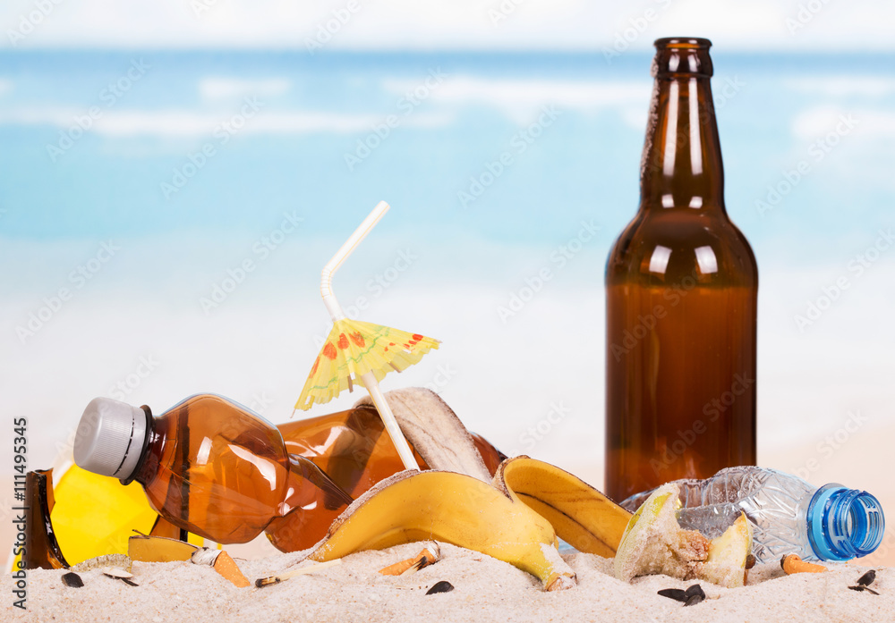 Glass and plastic bottles, food waste in sand against sea. Glass and plastic bottles, food waste in sand against sea.
