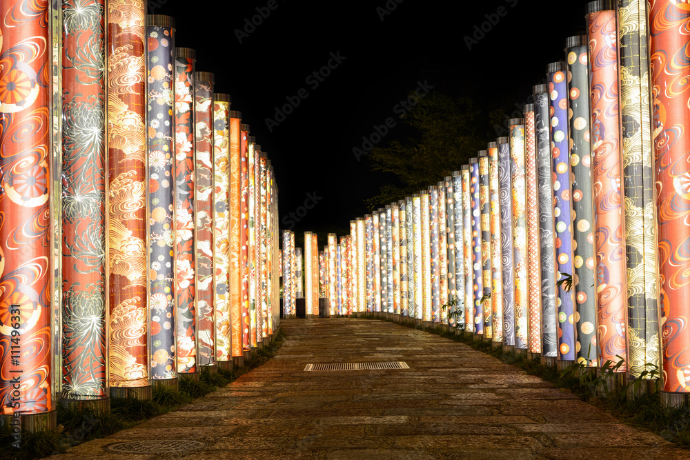 Naklejka premium Night illumination of kimono fabrics along a garden path in Kyoto, Japan