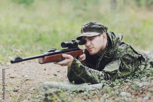 young soldier or hunter with gun in forest