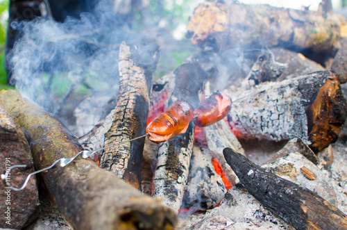 Two sausage on fire in camp. grilled sausages on open flame in the forest.
