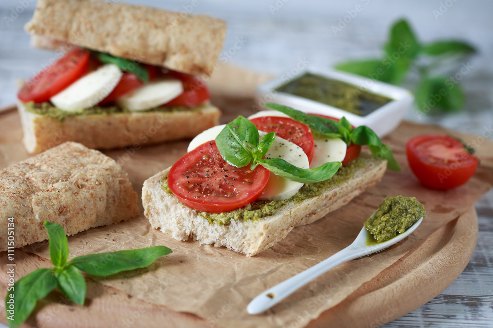 Closeup of a fresh sandwich with mozzarella, tomatoes, pesto and