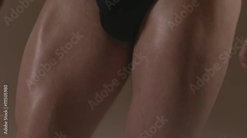 Brutal guy showing his muscles. Quadriceps (leg muscles). Ungraded