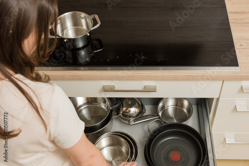 Woman in front of modern cooker with open drawer under the stove