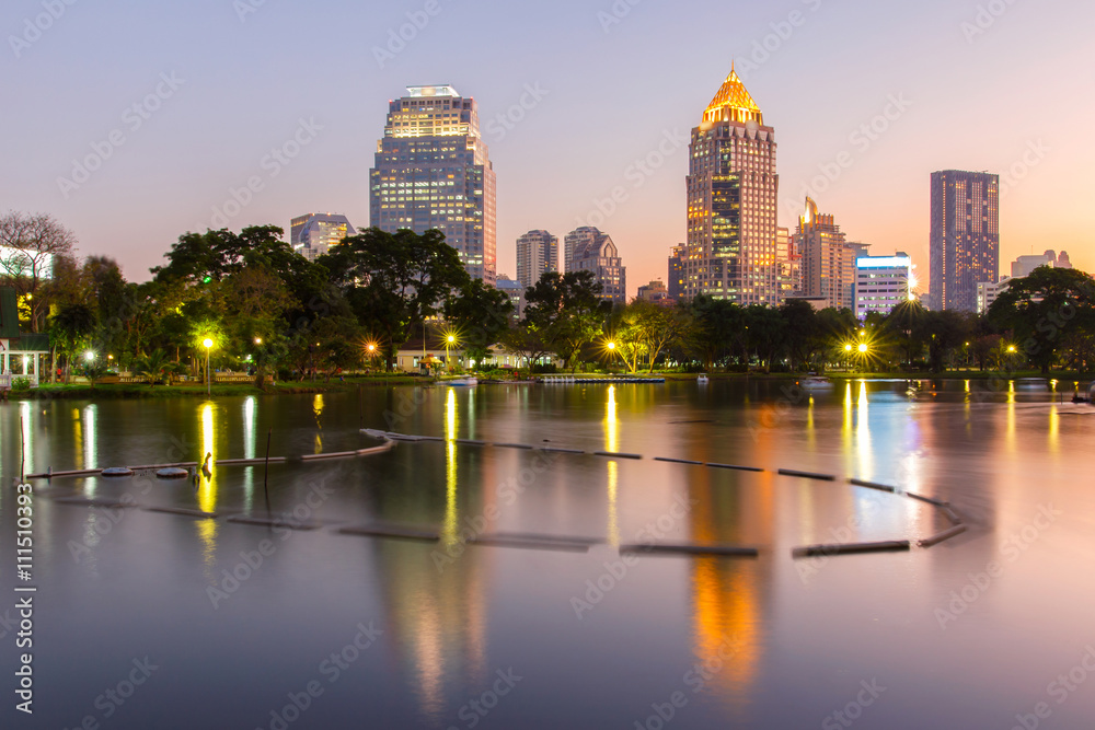 Fototapeta premium Business district cityscape from a park with Twilight Time from Lumpini Park, Bangkok, Thailand