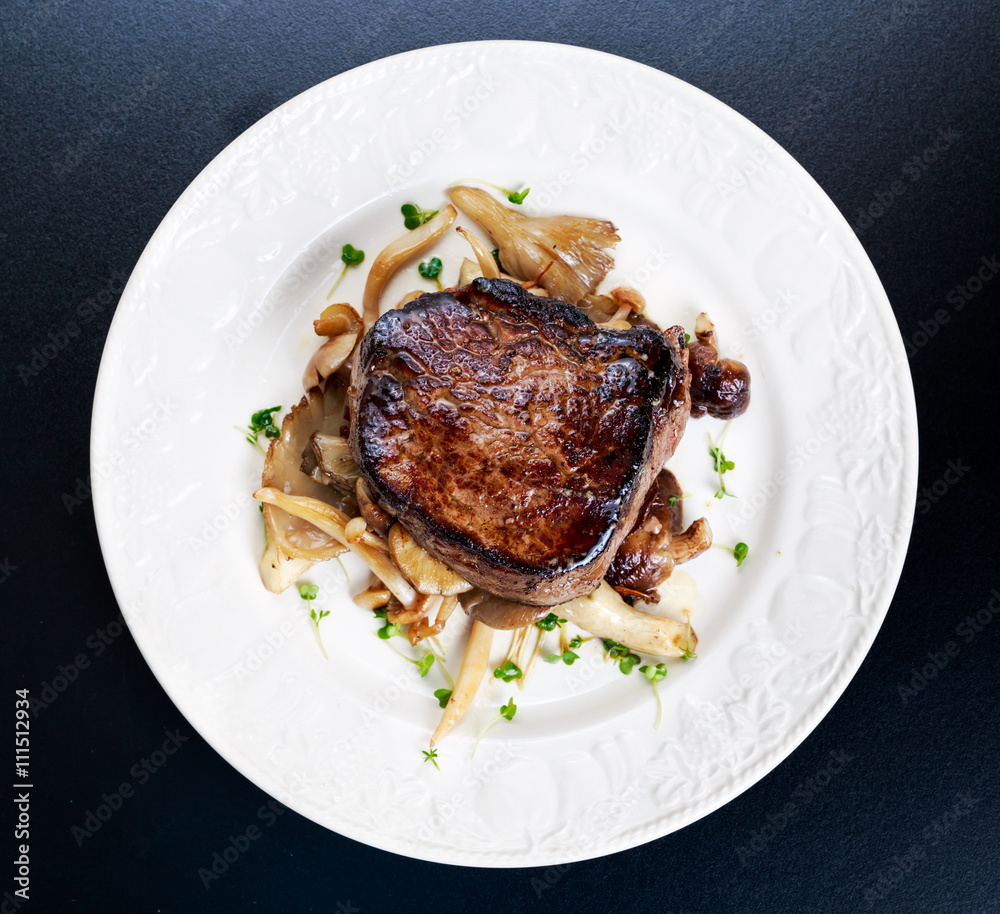 Tasty Beef Mignon steak with mushrooms and herbs on plate. Tasty Beef Mignon steak with mushrooms and herbs on plate.
